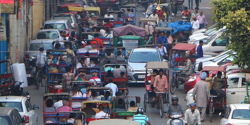 A picture of a bustling street of the Chandni Chowk Market with traffic moving through