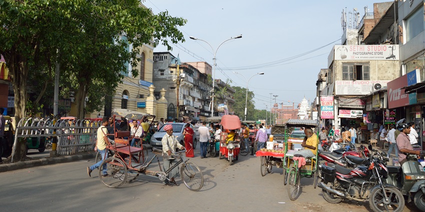 Busy Chandni Chowk road with shops, rickshaws, and pedestrians in Old Delhi market