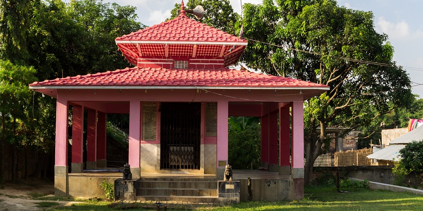 A picture of the frontal view of a temple surrounded by trees and greenery
