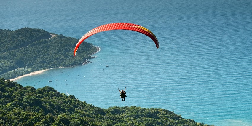 A person soaring high over forests while observing the natural beauty of the place.