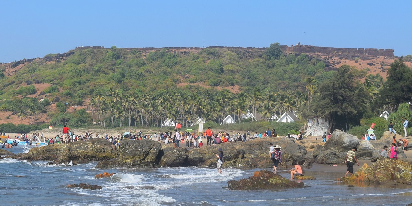 A picture of a fort in Goa taken from a distance with a beach in front
