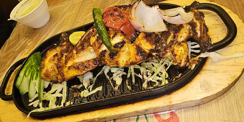 Grilled chicken tikka pieces served on a plate, garnished with onions and lemon, representing a flavorful and popular Indian dish.