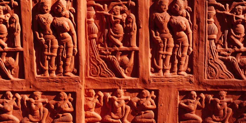 A picture of an old carved sculpture on a temple with human figures being portrayed.