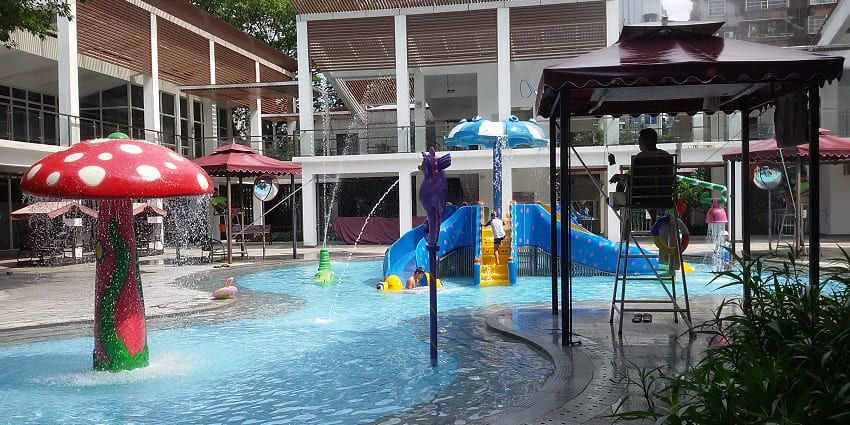 A picture of a children's pool at a water park with a big mushroom like rain structure in the middle