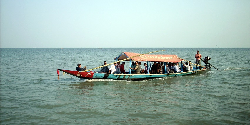 Sunset at Chilika Lake with serene water waves with a group of people on a big boat.