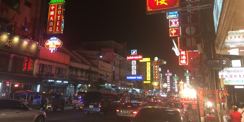 Bangkok nightlife for couples in Chinatown Street, with restaurant logos and passing cars