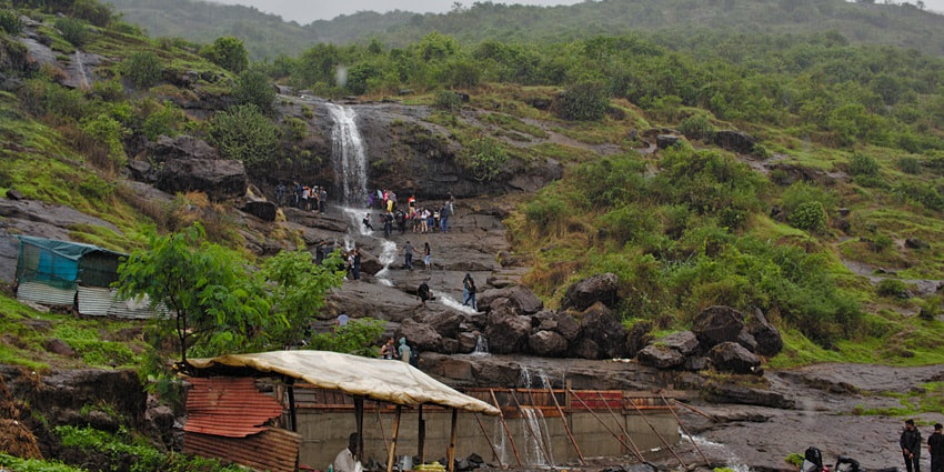 Waterfalls cascading down rocks surrounded by lush green forest.
