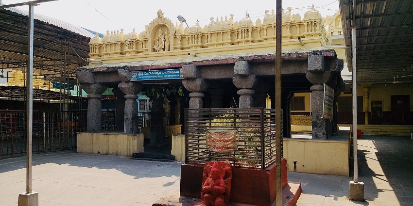 A historic temple with stone pillars and intricate carvings, partially covered by a roof.
