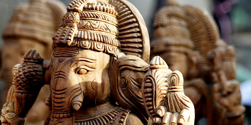 Wooden Ganesha figurines arranged on a surface, showcasing intricate carvings and detailed craftsmanship.