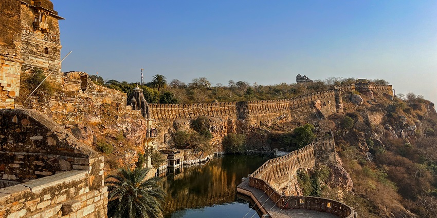 A huge Chittorgarh fort with walls and towers and rich foliage around the place.
