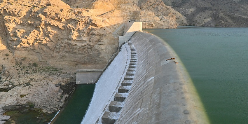 Peaceful view of Choral Dam surrounded by lush green hills and clear water during the day.