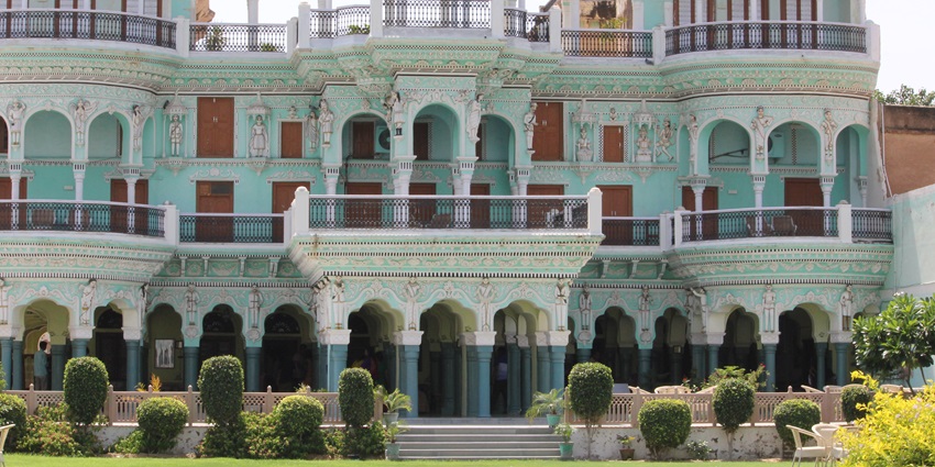 A frontal view of a majestic palace in Churu, Rajasthan with a lush garden area in front of it