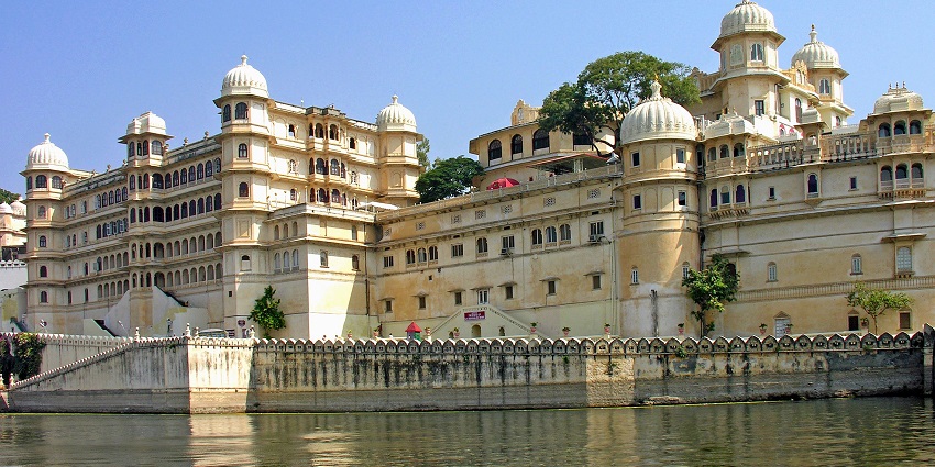 A mesmerising view of the city palace with a body of water surrounding it during the day.