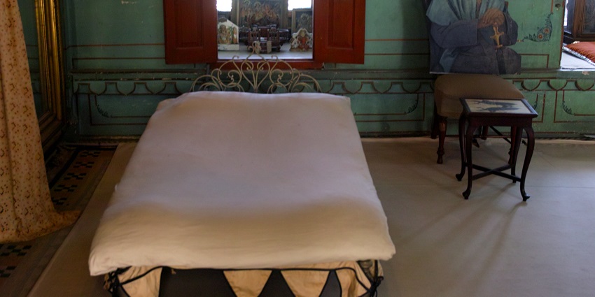 The City Palace Museum in Udaipur, showcasing a richly decorated room with traditional furnishings and intricate wall designs.