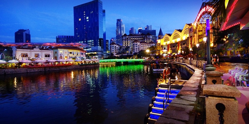 Colorful riverside Clarke Quay buildings reflecting on Singapore River at night