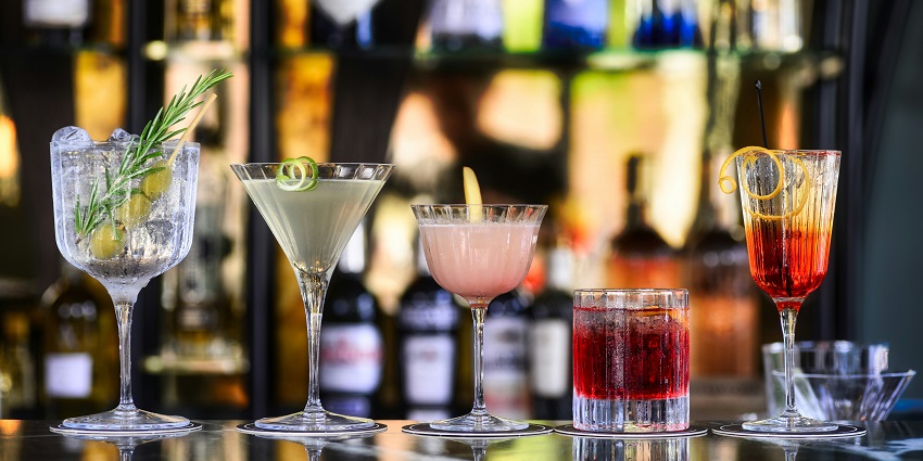 Clear cocktail glasses filled with vibrant pink liquid, set against a soft background.