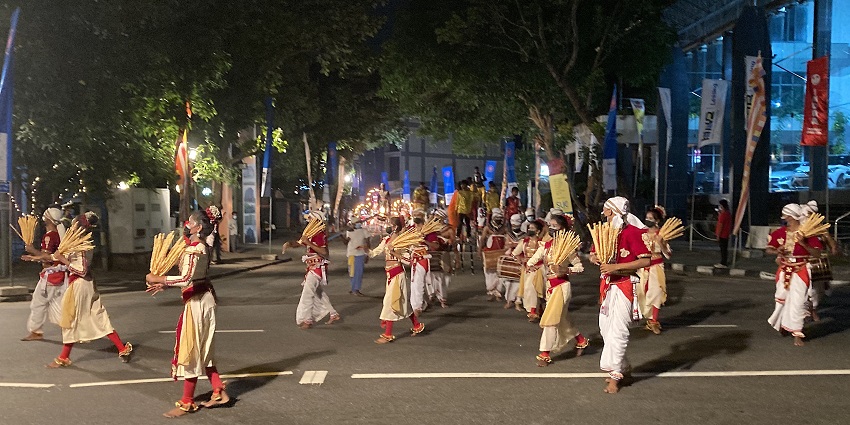 A breathtaking view of people wearing colourful costumes dancing on the road at night.