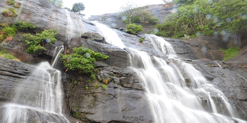 A picture showing Courtallam Main Falls cascading from a height on rocks.