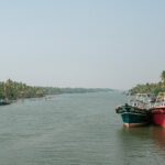 A picture of a boat sailing in a river with an island and greenery visible in the background at a distance