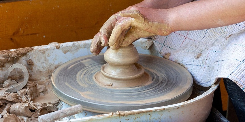 Hands shaping clay on a pottery wheel, reflecting the artistry of traditional Bhutanese craftsmanship.