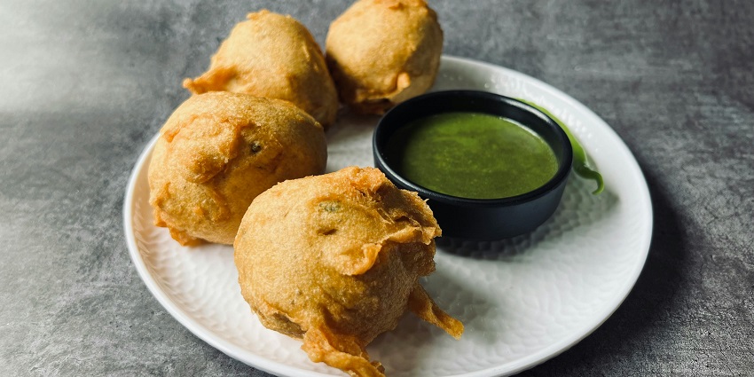 A glimpse of crispy vada served with green chilli chutney on a white ceramic plate.