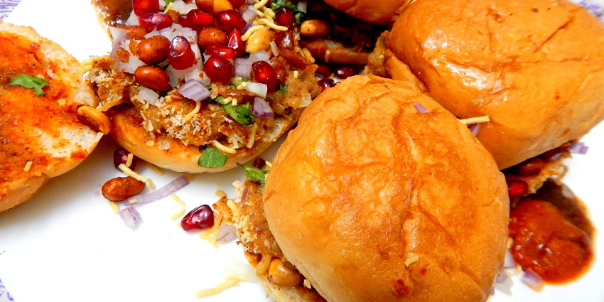 Dabeli is a spiced potato mixture served in a bun with chutney, sev and pomegranate seeds.