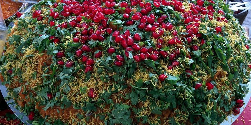 A view of a plate full of Dabeli with chutneys and garnishes.
