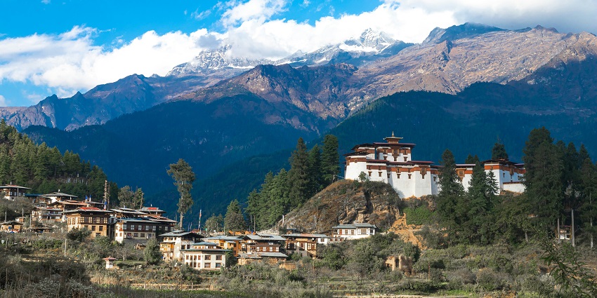 Image of Drukgyel Dzong in Bhutan surrounded by lush green mountains under clear blue sky