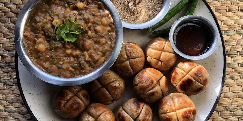 Dal Baati Churma is a famous dish with baked wheat balls, spicy lentils, and sweet Churma.