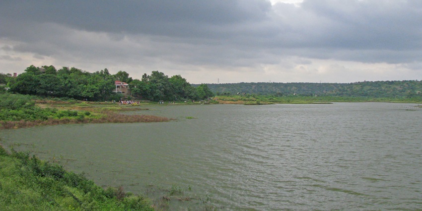 A serene view of the Damdama Lake featuring shimmering waters and lush greenery.