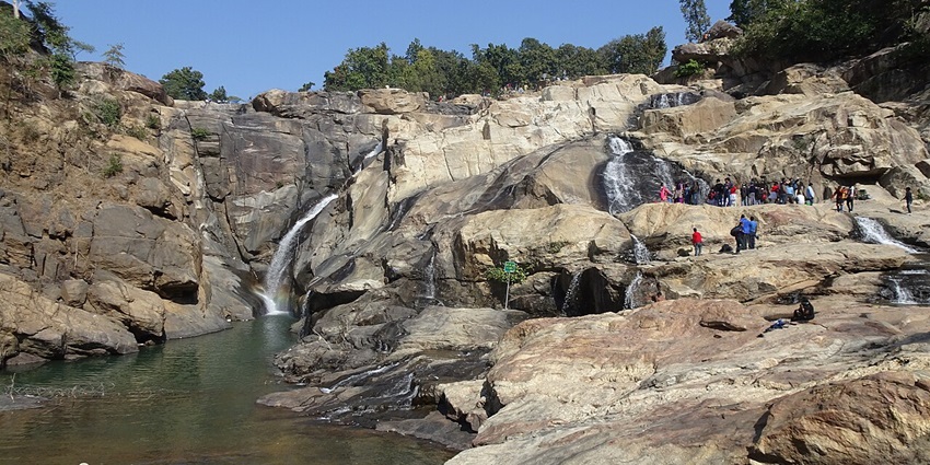 Image of Dasam waterfall in rugged terrain, water cascading down rocky escarpment.