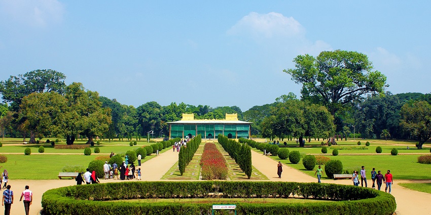 A big garden with a large path down the middle of it with a large palace-like structure.