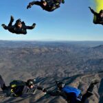 A mesmerising view of a group of people enjoying skydiving in clear blue skies in the day.