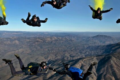 A mesmerising view of a group of people enjoying skydiving in clear blue skies in the day.