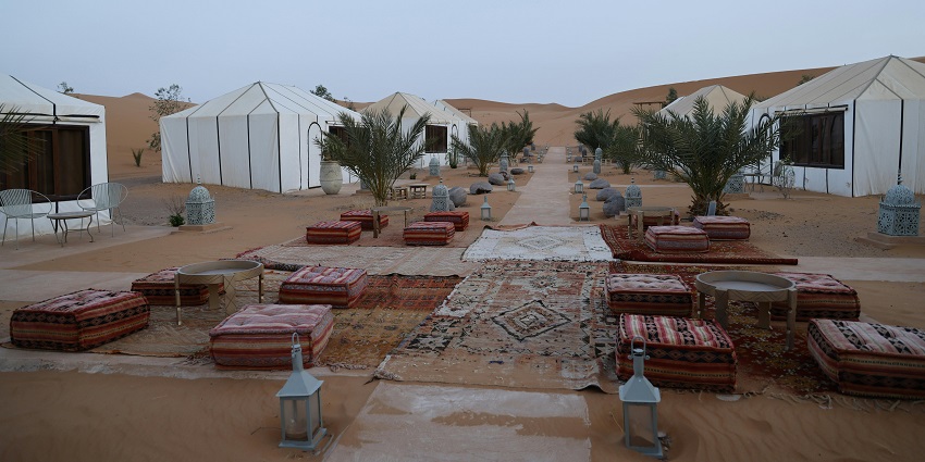 A glimpse of desert camps surrounded by sand dunes featuring a colourful courtyard.