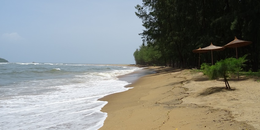 The beach is surrounded by lush greenery, featuring umbrellas at the coastline, one of the well-known beaches near Belgaum.