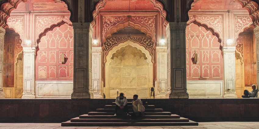 A picture of a traditionally designed South Indian temple in Delhi with people sitting on stairs