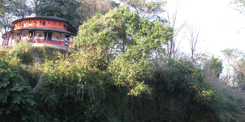 A view of Ghumauro Ghar at Devi's Falls, a traditional structure near the waterfall.