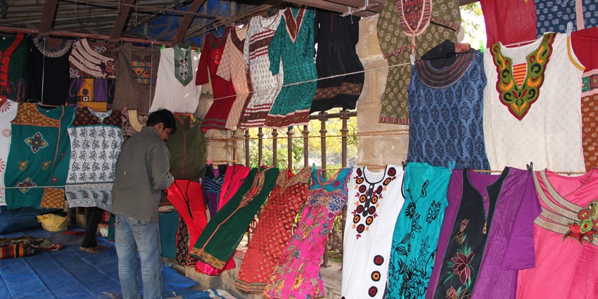 View of shoppers browsing through the cloth shops lining Dhalgarwad Market for street shopping in Ahmedabad.