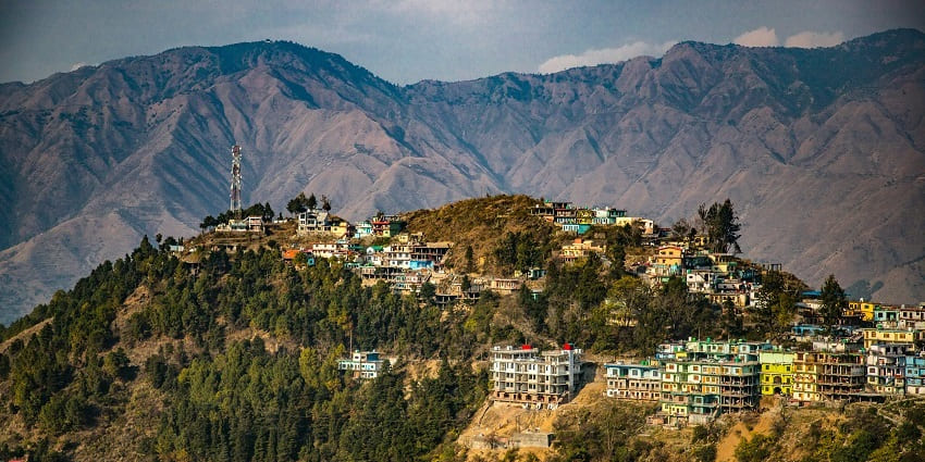 Image of scenic view of Dhanaulti, showcasing lush green hills and a clear blue sky.