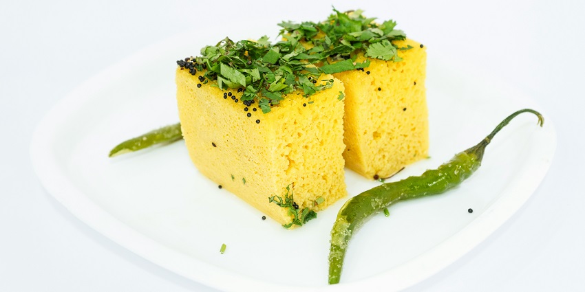 A glimpse of soft and fluffy Dhokla garnished with coriander leaves and green chillies.