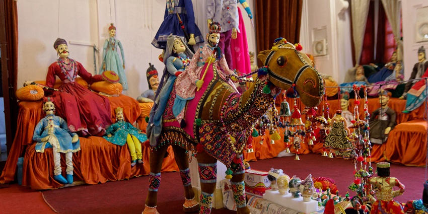 Antique ceramic dolls are displayed in a museum setting, showcasing historical artistry.
