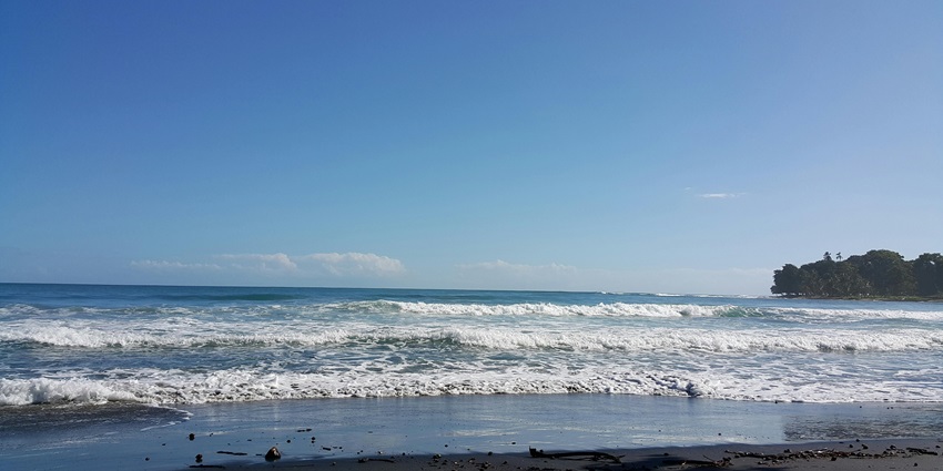 Serene beach sunrise with soft clouds and calm waves, evoking peaceful vibes for all.
