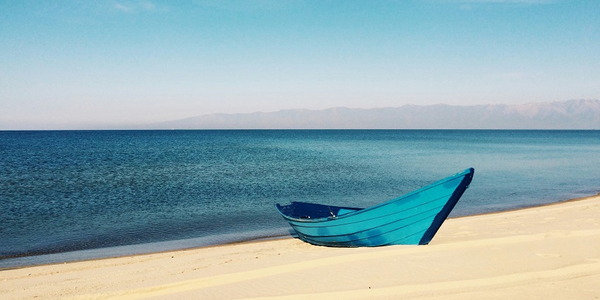A peaceful and scenic view of a Thai beach with crystal-clear waves and distant boats.