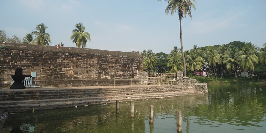 A wide angle view of a pond near Draksharamam temple, highlighting grand architecture and serene environment