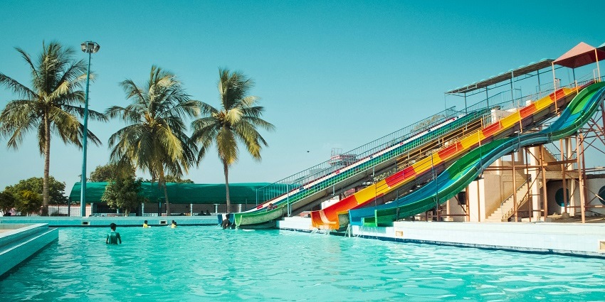 A beautiful view of colourful slides with palm trees and a clear sky in the background.