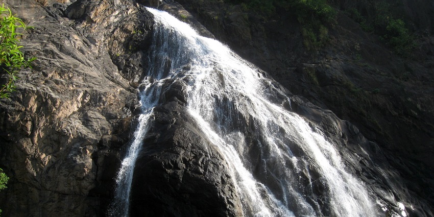A picture of a waterfall taken from down under showing the water slowly cascading down the rocky hill
