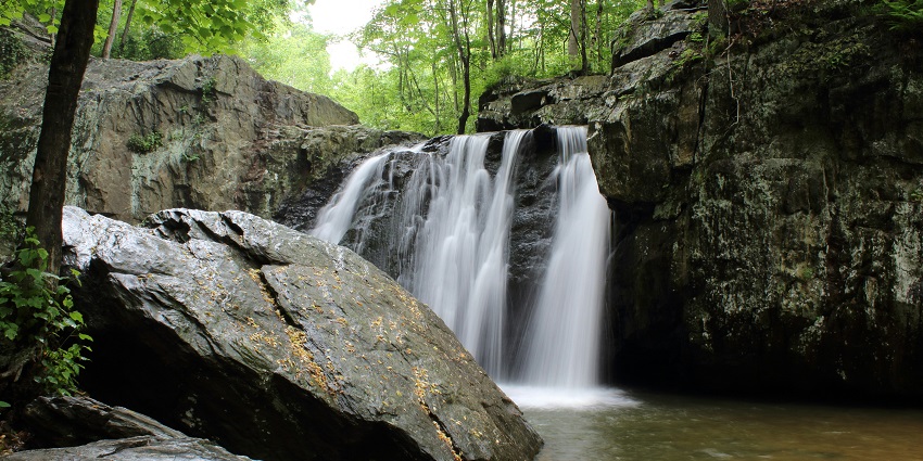 A scenic view of shimmering waters cascading through the rocky cliffs at Dudhsagar Waterfalls.