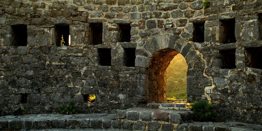 An old fort structure with a small entrance against a beautiful backdrop
