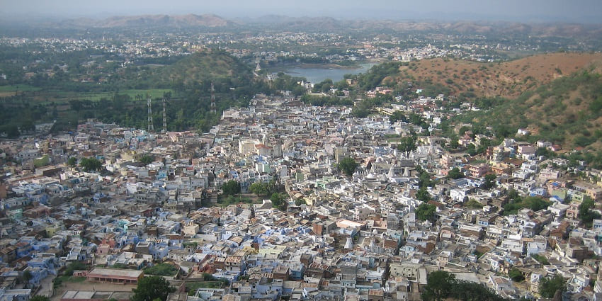 Scenic aerial view of Dungarpur, Rajasthan, India, with dense houses, hills, and a lake.